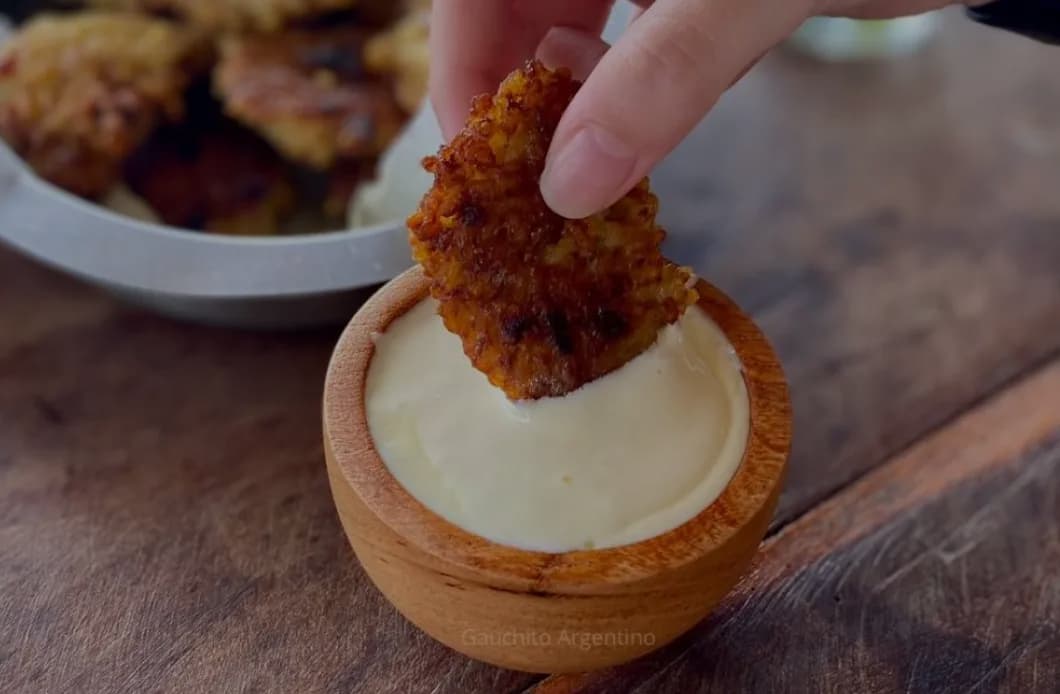 A hand dipping food into a bowl